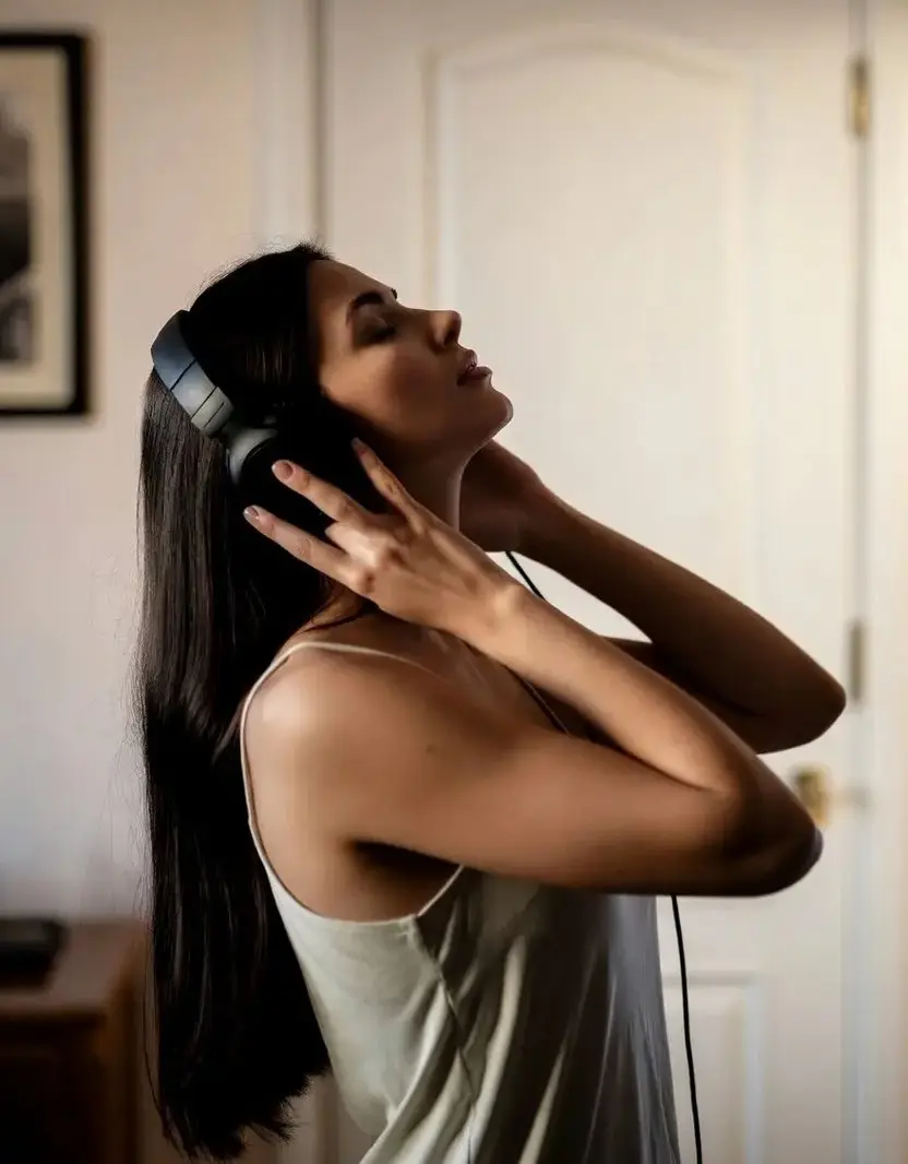 Femme brune écoutant de la musique avec un casque audio chez elle, ambiance intime et introspective inspirée de The Moment (2026) de Aidan Zamiri avec Charli XCX, Rachel Sennott et Alexander Skarsgård, bande originale hyperpop incluant 365, Boom Clap et Club Classics